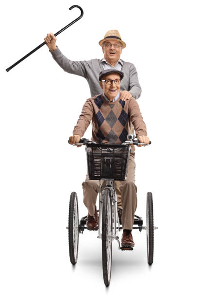 Two elderly men on a trycicle with a walking cane raised up Two elderly men on a trycicle with a walking cane raised up isolated on white background adult tricycle stock pictures, royalty-free photos & images