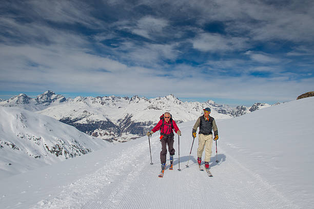 Two elderly men practice ski mountaineering stock photo