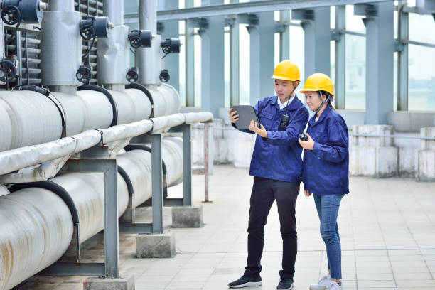 Two Engineer Colleagues Examining Cooling Tower Equipment Two engineer colleagues examining to cooling tower equipment. oil refinery stock pictures, royalty-free photos & images
