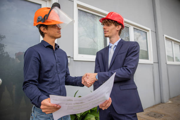 two engineers shake hands while looking at a floor plan during construction. - plattegrond kind stockfoto's en -beelden