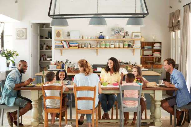 Two families having lunch together in the kitchen at home  dining table stock pictures, royalty-free photos & images