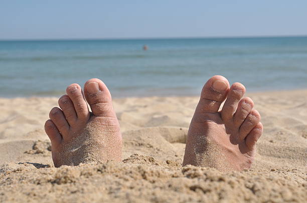 Two feet buried in sand Two man feet buried in sand human feet buried in sand. summer beach stock pictures, royalty-free photos & images