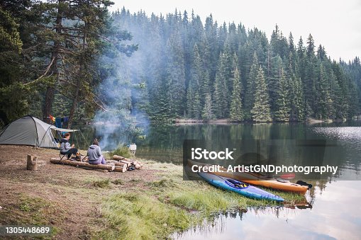 istock Two female friends sitting next to campfire in a wild camp in the mountain. 1305448689