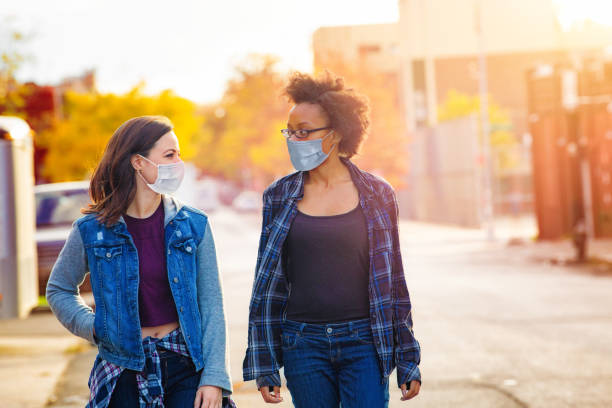 duas amigas andando por um beco do brooklyn usando máscaras faciais - colagem mulheres conversa - fotografias e filmes do acervo