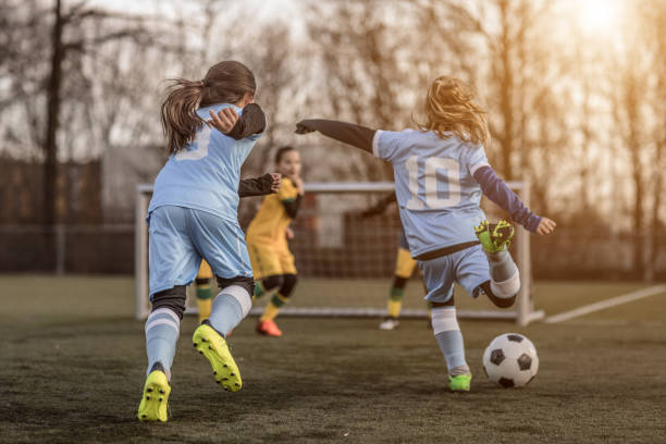 Two Female Girl Soccer Teams playing a football training match in the Spring outdoors Two Female Girl Soccer Teams playing a football training match in the Spring outdoors equipación fútbol stock pictures, royalty-free photos & images