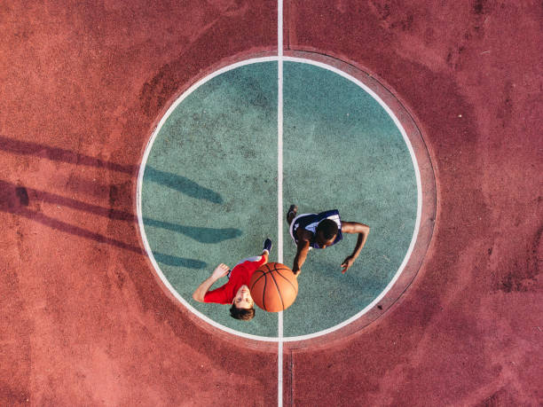 Two friends are jumping to take a basketball ball on the center field stock photo