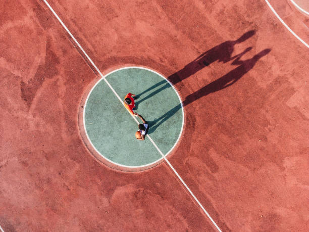 Two friends are playing basketball together, holding hands before the start - Aerial point of view stock photo