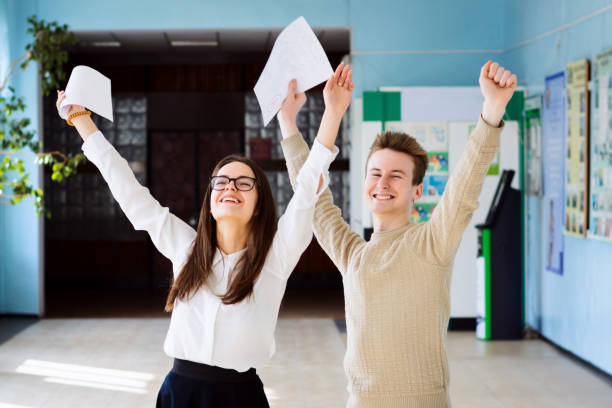 Two friends happy after their exams, raising hands up and expressing amusement of getting excellent grades for their work Happy students after examination students exam results stock pictures, royalty-free photos & images
