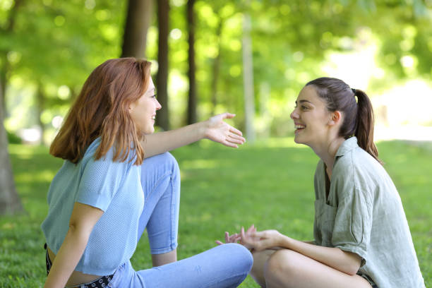 Two friends talking sitting in a park stock photo