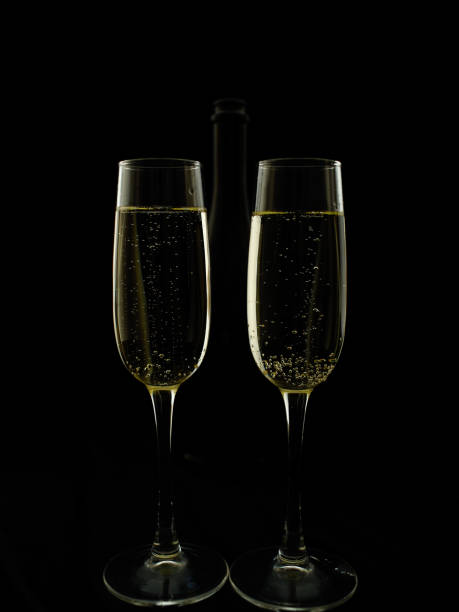 Two glasses and a bottle of champagne on a black background. stock photo