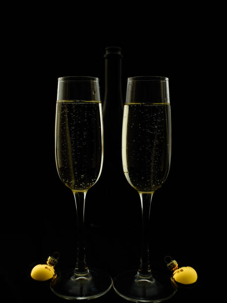 Two glasses and champagne bottle on a black background in New Year's style. stock photo
