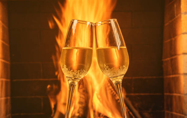 Two glasses of champagne in front of a cozy burning fireplace in country house. stock photo