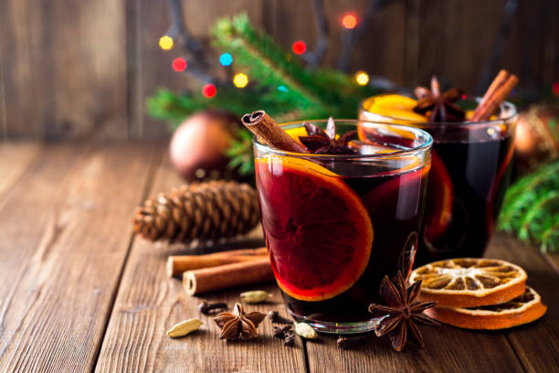 Two glasses of christmas mulled wine with oranges and spices on wooden background. stock photo