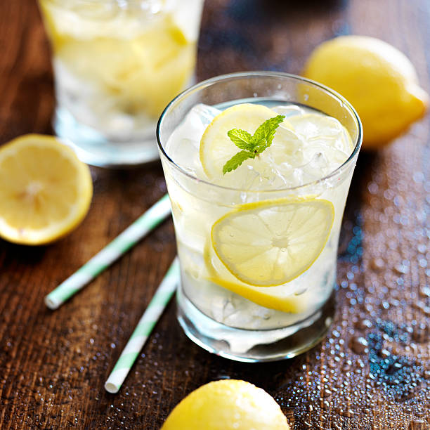 two glasses of lemonade shot close up with mint garnish and paper...