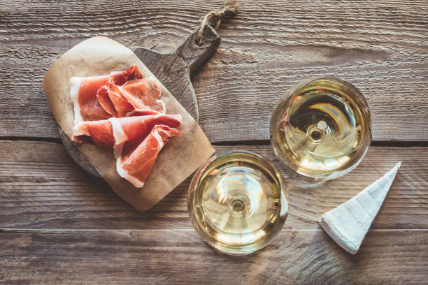 Two glasses of white wine Two glasses of white wine with Brie and Prosciutto ham prosciutto stock pictures, royalty-free photos & images