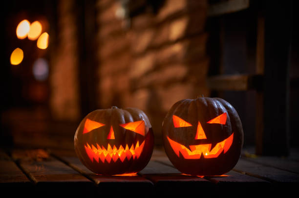 Two glowing Halloween Pumpkins at the entrance to an old wooden house stock photo