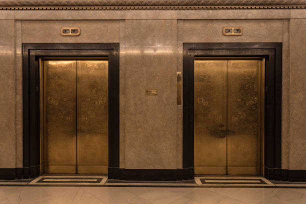 Two gold door elevators in a marble lobby stock photo