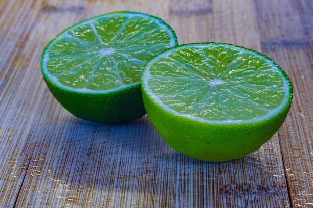 Two green lime halves on chopping board closeup stock photo