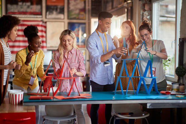 two group of employees making paper towers, separated in different competitive teams. stock photo