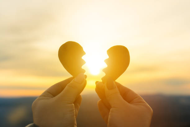 Two hands and a broken heart on a sunset background. stock photo