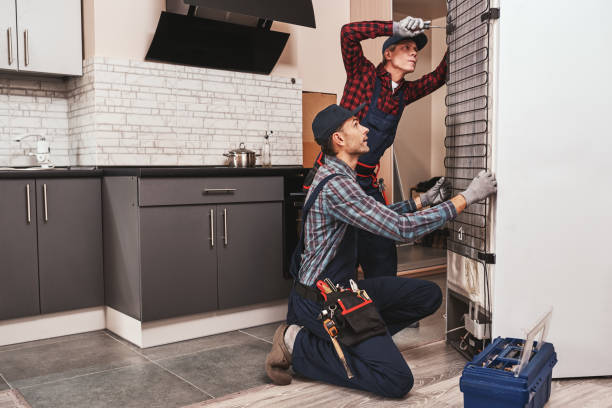 Two handymen with refrigerator. Young men mechanics checking refrigerator Two handymen with refrigerator. men mechanics checking refrigerator with screwdriver. They assist each other. Side view Refrigerator Technician  stock pictures, royalty-free photos & images