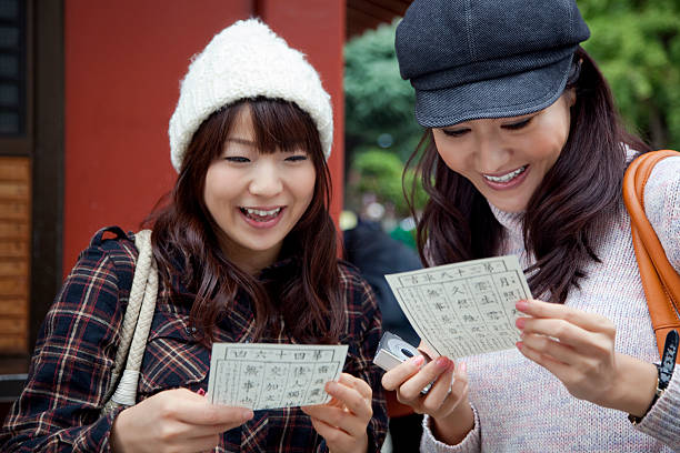 2 つの幸せな若い女性の読書 omikuji フォルテュネペーパーズ - おみくじ ストックフォトと画像