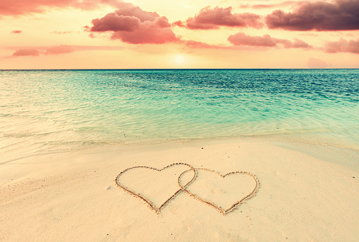 Two hearts on sand on tropical beach at sunset. Valentines day. Maldives islands.