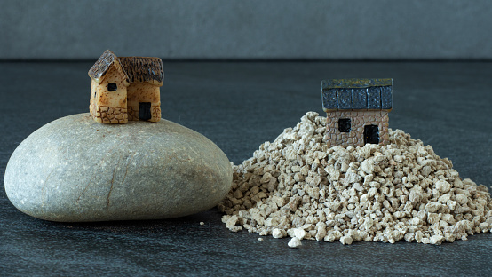 Two houses, one built on a rock, and the other built on a sand. Jesus Christ parable of wise and foolish Christian. The biblical concept of faith and obedience to God. A close-up.