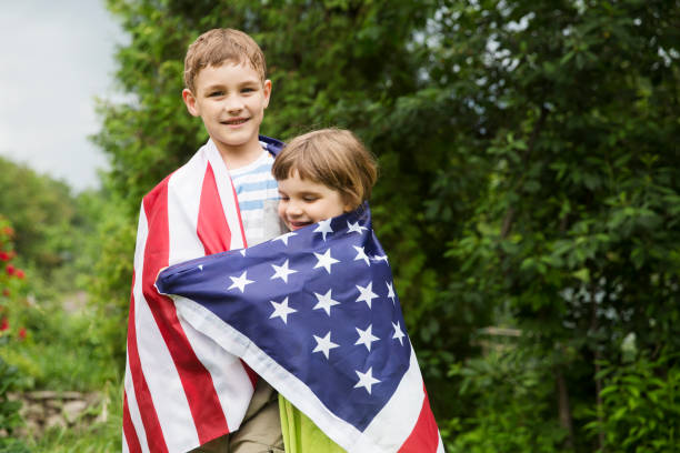 двое детей брат и сестра с американским флагом на открытом воздухе. день независимости. соединенные штаты празднуют 4 июля. - july 4 стоковые фото и изображения