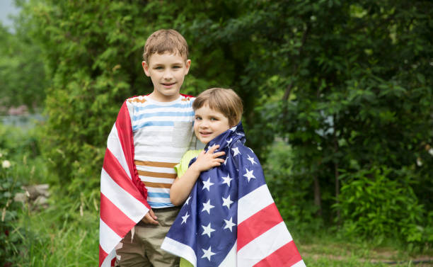 двое детей брат и сестра с американским флагом на открытом воздухе. день независимости. соединенные штаты празднуют 4 июля. - july 4 стоковые фото и изображения