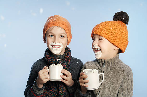 Two kids having fun in the snow drinking hot chocolate stock photo
