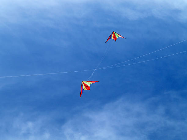 Two kites in the sky with tangled up ropes stock photo