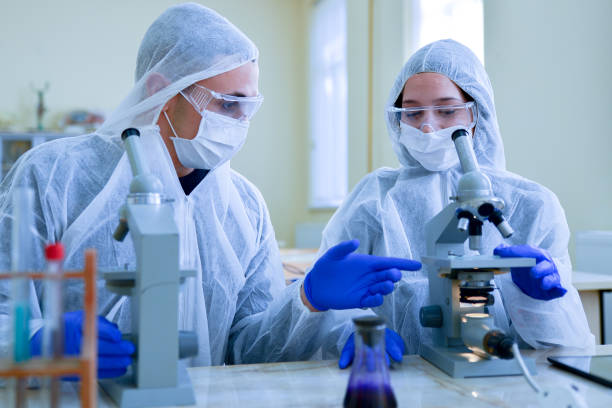 Two laboratory assistants examine cells with cancer status stock photo