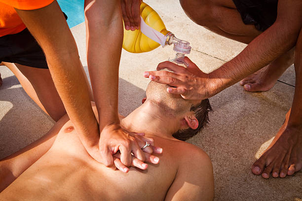 Two lifeguards giving cardiopulmonary resuscitation (CPR) to a drowned man stock photo