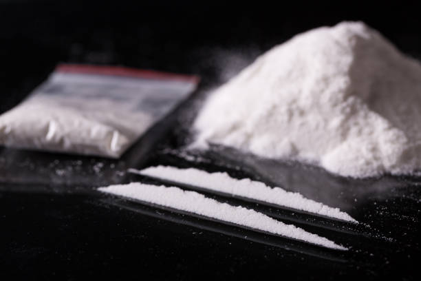 Two lines and pile of cocaine on black background stock photo