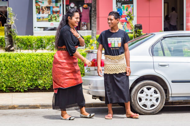 dwa lokalne rodzimych polinezyjskich uśmiechniętych nastolatków, dziewczyna i chłopiec, w tradycyjnym zamknięciu - spódnice taovala i tupenu. ulica stolicy nuku'alofa, tongatapu - tonga zdjęcia i obrazy z banku zdjęć