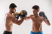 Two male boxers training on white background
