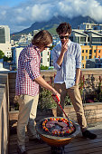 Friends having a barbecue on outdoor rooftop terrace with skewer kebabs
