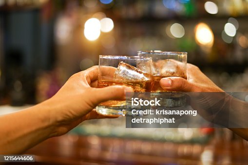 istock two men clinking glasses of whiskey drink alcohol beverage together at counter in the pub 1215644606