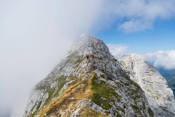 Two men on the steep and cloud covered ridge leading to the summit of Mount Guffert at Rofan mountains, Tirol, Austria stock photo