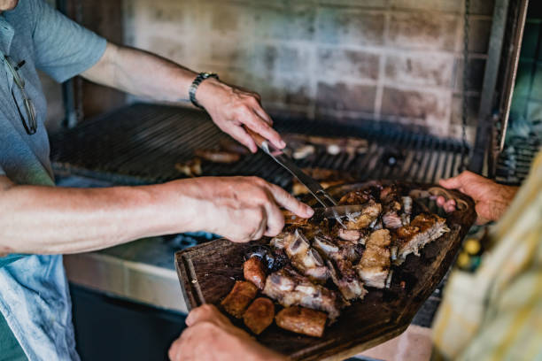 Two men serving meat for lunch, asado Two men cutting and serving barbecue meat at home for family. argentina food stock pictures, royalty-free photos & images