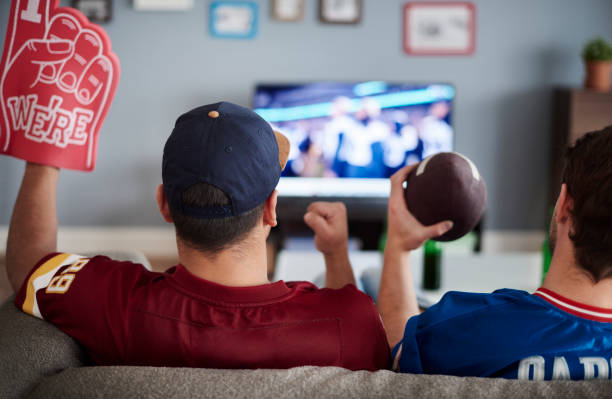 Two men with foam hand and baseball equipment  watching stock pictures, royalty-free photos & images