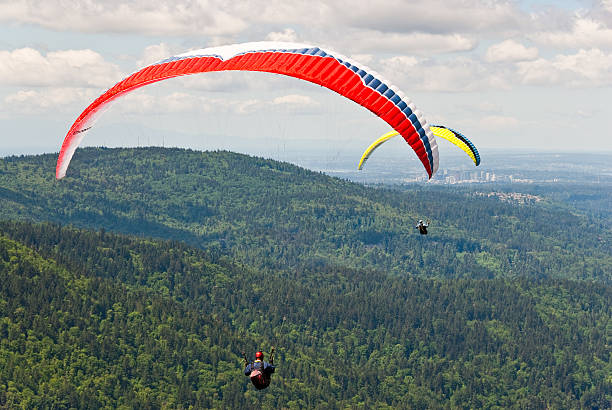 Two Paragliders Tiger Mountain State Forest, Washington, USA - May 09, 2016: Poo Poo Point is a popular paragliding spot on Tiger Mountain in the Cascade Foothills near Issaquah. These two paragliders are soaring over the trees near Tiger Mountain. jeff goulden paragliding stock pictures, royalty-free photos & images