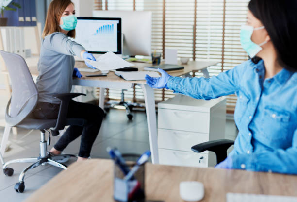 Two people in office passing documents with keeping a distance Two people in office passing documents with keeping a distance working stock pictures, royalty-free photos & images