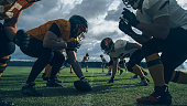 istock Two Professional American Football Teams Stand Opposite Each Other,  Ready to Start the Game. Defense and Offense Prepare to Fight for the Ball with Desire to Score Points and the Goal and Win. 1355085874
