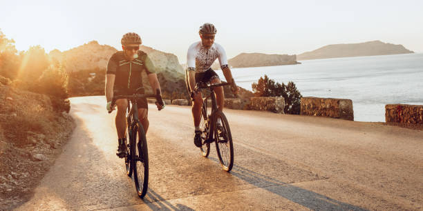 Two professional male cyclists riding their racing bicycles in the morning together stock photo