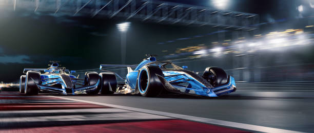 Two Racing Cars Moving At High Speed During Night Race Two blue toned racing generic racing cars racing at high speed close to each other on a generic racetrack near to a spectators stand, during a night race. With motion blur. racecar stock pictures, royalty-free photos & images