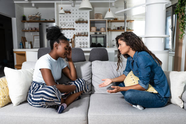 Two sad depressed and anxious diverse women talking at home. Female friends supporting each other. Problems, friendship and relationships difficulties care concept stock photo