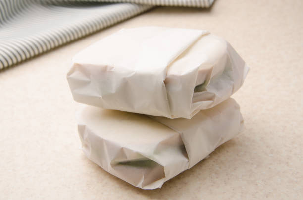 Two sandwiches wrapped in parchment paper on kitchen table Two sandwiches wrapped in parchment paper on kitchen table burger wrapped in paper stock pictures, royalty-free photos & images