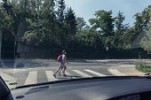 Two school kids on the pedestrian crossing, view from inside the car